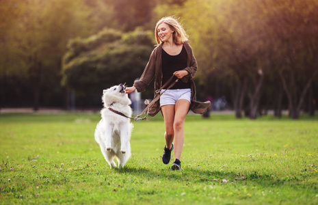 俏丽的女孩在公园玩和奔跑与萨摩耶狗