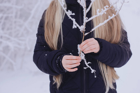 冬天的女孩吹雪。美丽快乐的青少年模特女孩在冬季公园玩得很开心。美丽的女孩在户外笑。享受大自然。