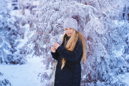 冬天的女孩吹雪。美丽快乐的青少年模特女孩在冬季公园玩得很开心。美丽的女孩在户外笑。享受大自然。