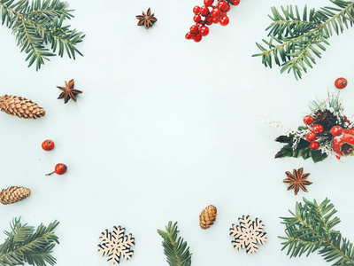 圣诞背景。 由圣诞树树枝红色浆果松果和木制雪花组成的框架。 平躺顶视复印空间