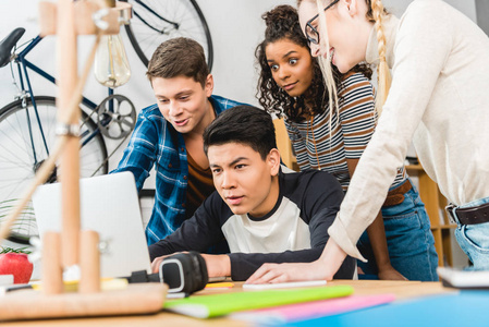 一群多文化的青少年在桌子上使用笔记本电脑