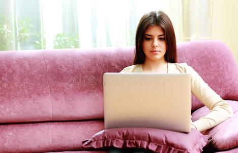 坐在沙发上用笔记本电脑的年轻美女