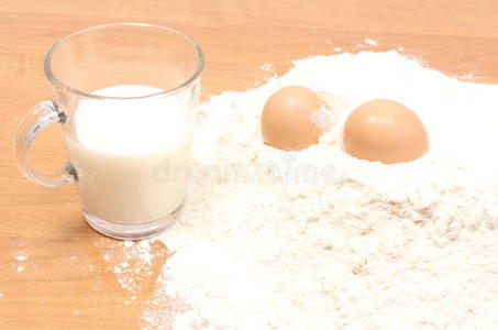 面粉，一杯牛奶和两个鸡蛋放在桌上