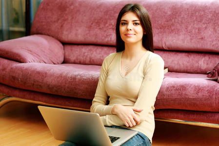 坐在地板上用笔记本电脑的年轻快乐女人
