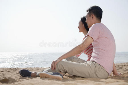 一对夫妇坐在沙滩上眺望大海