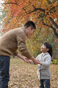 秋日，父女牵手，在公园里相望
