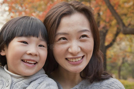 母亲和女儿在公园微笑的特写，秋天，肖像
