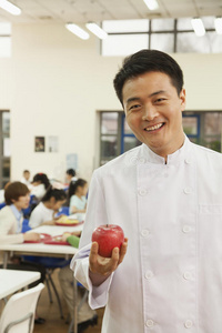 学校食堂拿着苹果的厨师画像图片