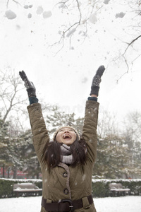 公园里向空中飞雪的年轻女子图片