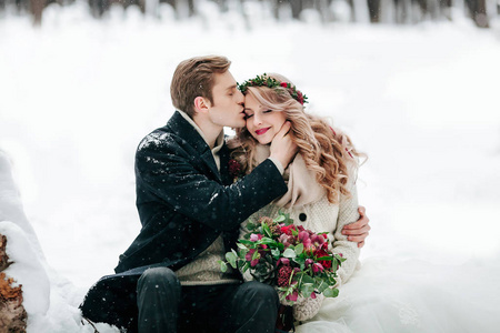 新郎在白雪背景的寺庙里亲吻他的新娘。艺术品.有选择地关注花束