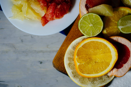 各种柑橘类水果切成片橙, 柠檬, 石灰, 柚子, 柚子和一杯橙汁。摊开在一个木制板和老式的白色板的背景自然
