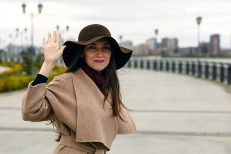 快乐时尚的女孩穿着带皮带和大帽子的问候显示手势.