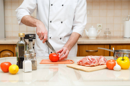 烹饪和家庭概念   男性的手切番茄在砧板上用锋利的刀的特写