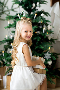 愉快可爱的小微笑的女孩与圣诞节礼物箱子。圣诞快乐, 节日愉快