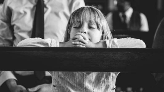 一个孩子在教堂里祈祷原始照片