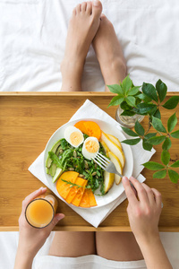 健康的饮食观念。女人在床上吃早餐。上景。