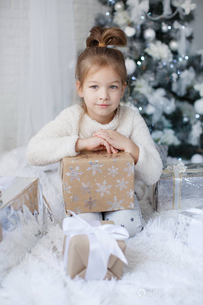 快乐的孩子5岁的女孩在圣诞节假期靠近一棵美丽的绿色圣诞树上面装饰