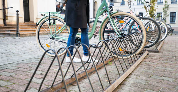 女孩停放她的自行车在街道在城市