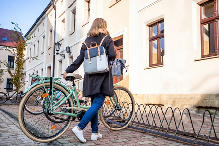女孩在旧城区的街道上停放她的老式自行车