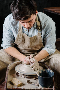 陶器 车间 陶瓷艺术概念与原始粘土与手，匠心之轮上工作的人一个男性的黑发造型用具附近的木桌和工具，掌握穿着围裙和一件衬衫