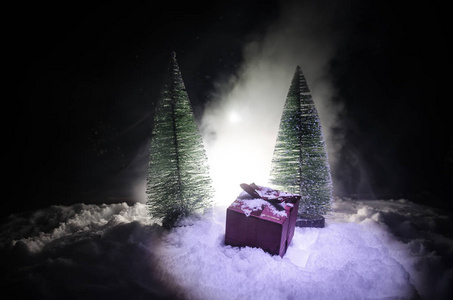红色圣诞节礼物箱子和冷杉树在雪。圣诞节家庭装饰与雪和树在黑暗背景下与拷贝空间
