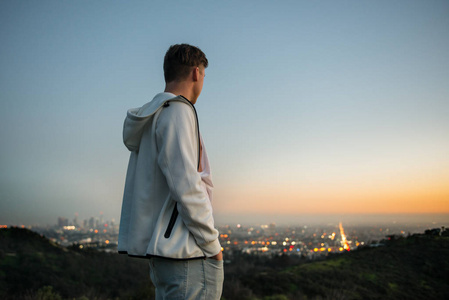 在洛杉矶好莱坞山观看城市日落的年轻人