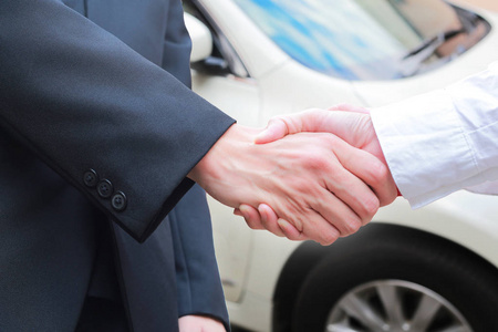 汽车销售商和商人握手在汽车经销商