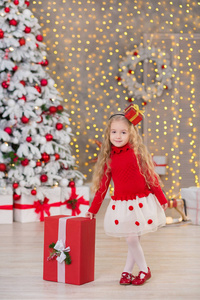 年轻美丽的女孩微笑, 坐在附近巨大的金色镜子大量礼物在毛皮圣诞绿色白色豪华圣诞树装饰品和在谎言之下礼物