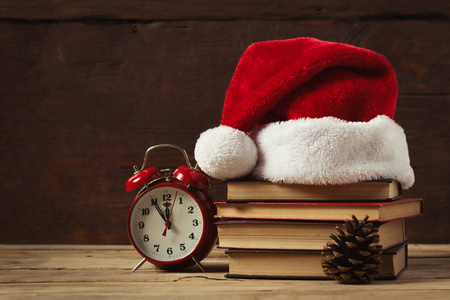 红色的闹钟, 冷杉锥。在书上圣诞老人的帽子, 在木