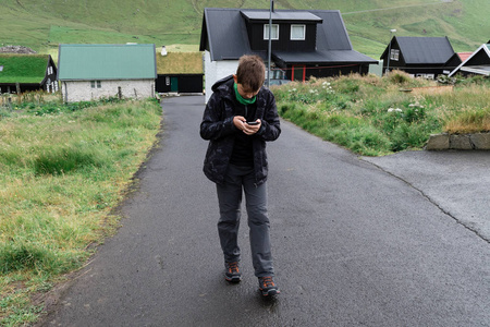 一个男孩走在法罗群岛周围玩智能手机