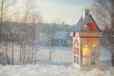 木老房子与蜡烛在雪和模糊的神奇的冬天风景背景
