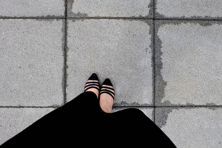 女性穿黑色连衣裙和黑色鞋子，女性站在瓷砖背景上，非常适合任何用途。