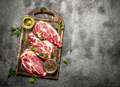 生肉背景。旧木板上有香草和香料的生牛排。论乡村背景