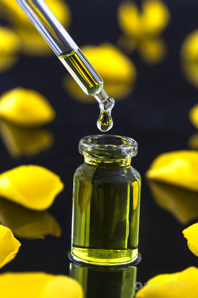 一瓶玫瑰精油黄色玫瑰花瓣在黑色背景