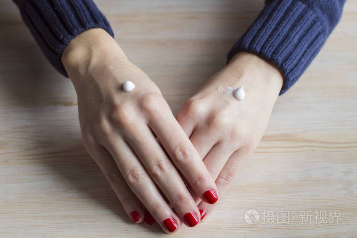 女性手用红色修指甲和白奶油