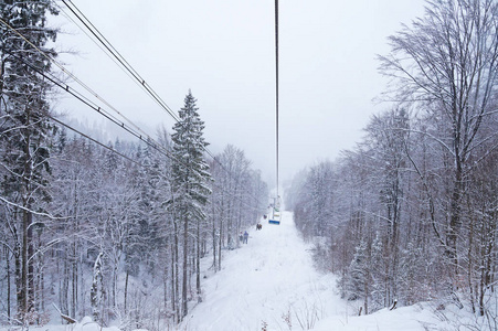 走到滑雪道。 椅子的升降台上升到积雪覆盖的树木之上。