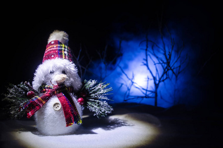新年。雪人为新年卸礼物。白色的雪人在傍晚的背景下被圣诞树包围。玩具装饰