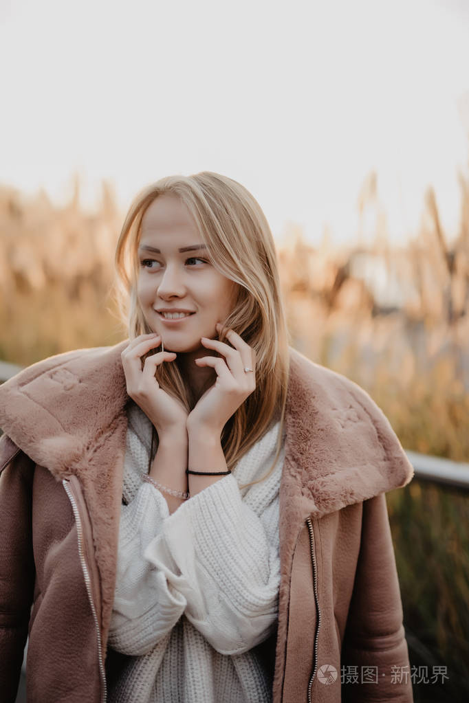 快乐的年轻妇女在秋天的季节在城市街道在日出