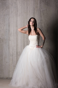新娘在美丽的婚纱礼服与肩上的混凝土墙壁构成