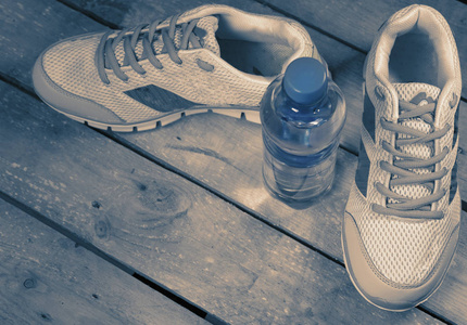 运动运动鞋和木制背景的饮用水