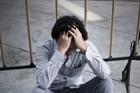 沮丧的强调年轻的亚洲商人用手捂着额头, 在外面办公室感到失望照片