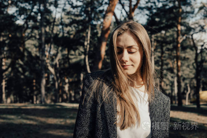 公园背景的树木上，一位美丽的年轻女子在镜头前摆姿势