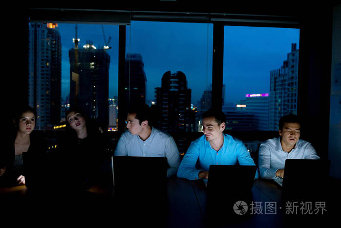加班概念. 一群年轻的商业团队深夜在会议室工作,试图完成他们的任务.