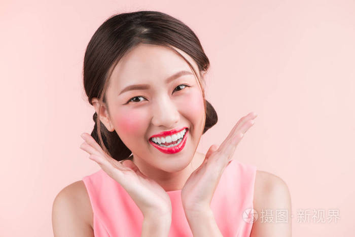 漂亮的年轻迷人的微笑女人靠近粉红色的背景