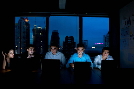 加班概念. 一群年轻的商业团队深夜在会议室工作,试图完成他们的任务.