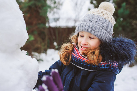 快乐的小女孩在后院的圣诞假期做雪人。 儿童冬季户外活动。