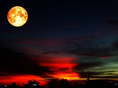 全血月在五颜六色的天空在橙色深灰色云彩