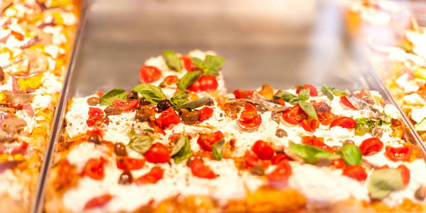 意大利比萨饼在意大利比萨饼店的一个摊位上拿走了一些东西，里面有西红柿黑色橄榄和奶酪