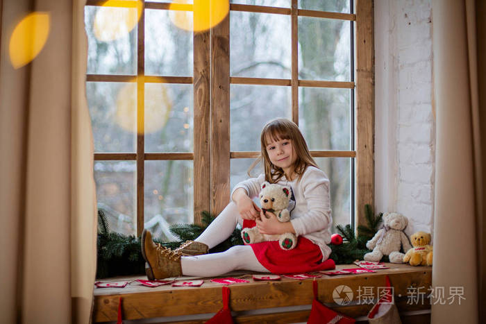 快乐的小女孩坐在房间里的窗台上有节日装饰