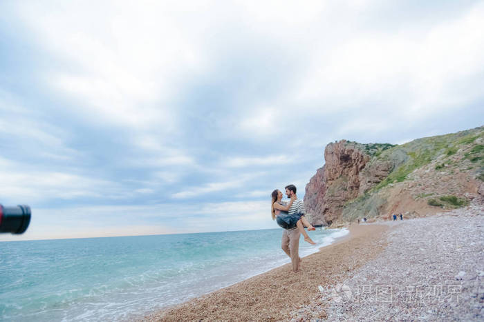 快乐的大胡子男人背着他美丽的女人走在海边整整齐齐